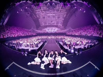 Lia, Yuna, Ryujin, Yeji, and Chaeryeong are all sitting on the stage with the crowd behind them.